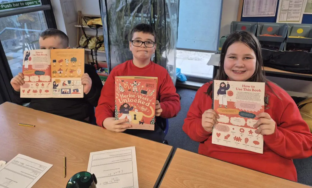 Primary school children show off the Heriot-Watt Unlocked booklet.