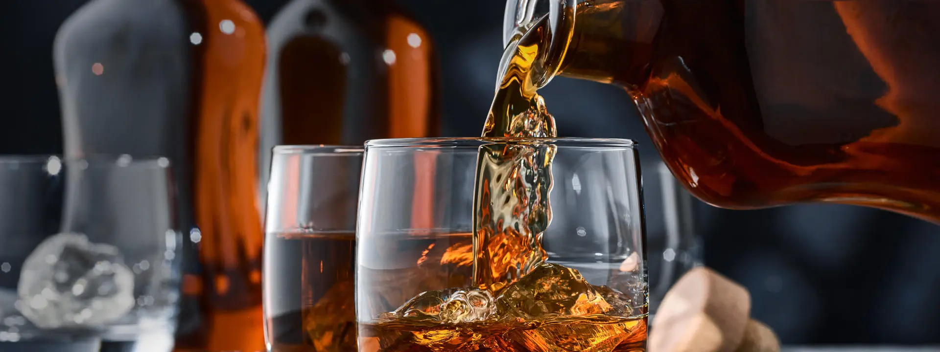 Rum being poured from a bottle into a glass with ice