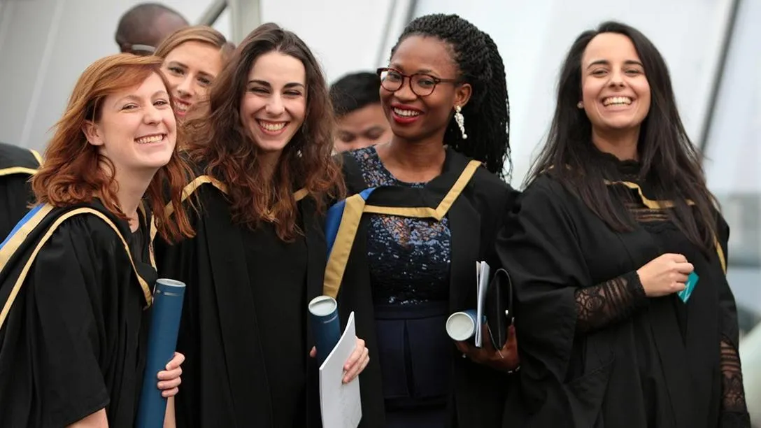 A group of graduates smiling in their graduation robes. 