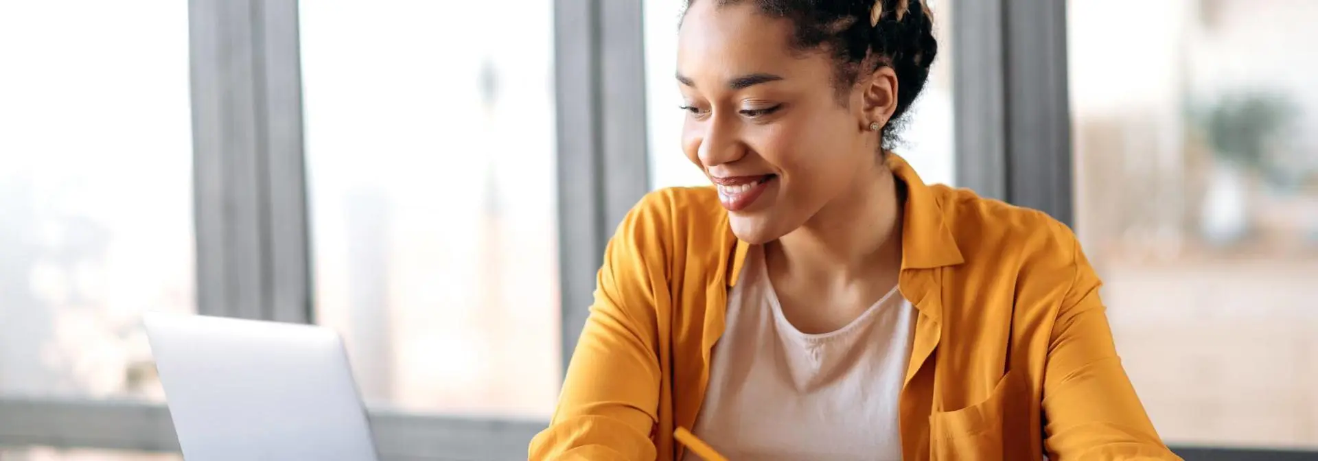 Woman works from home at a computer writing notes