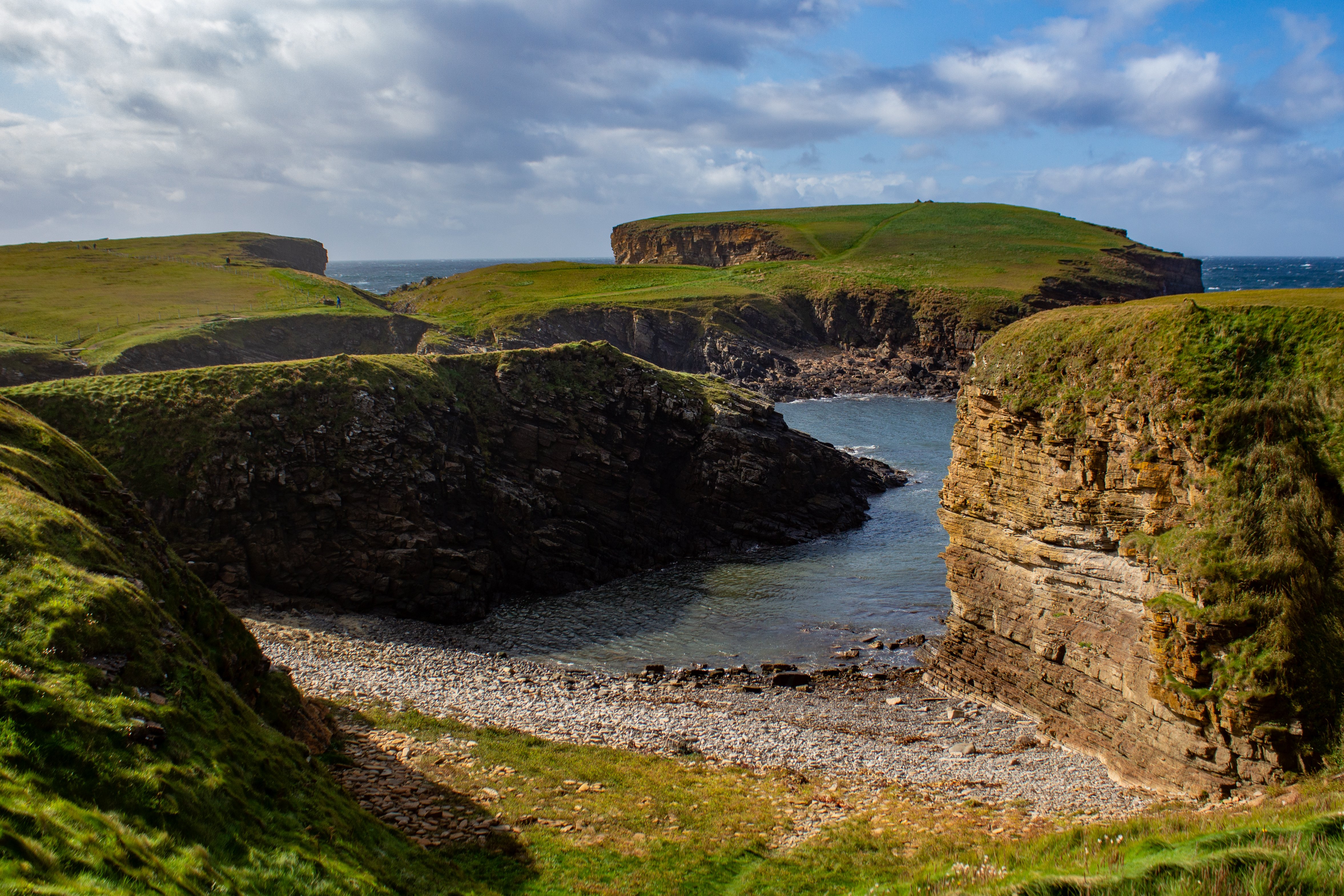 Coastline with green hills and rocky outcrops.