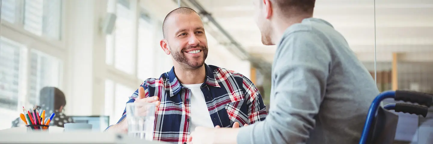 An individual in a wheelchair working in an office with a colleague.