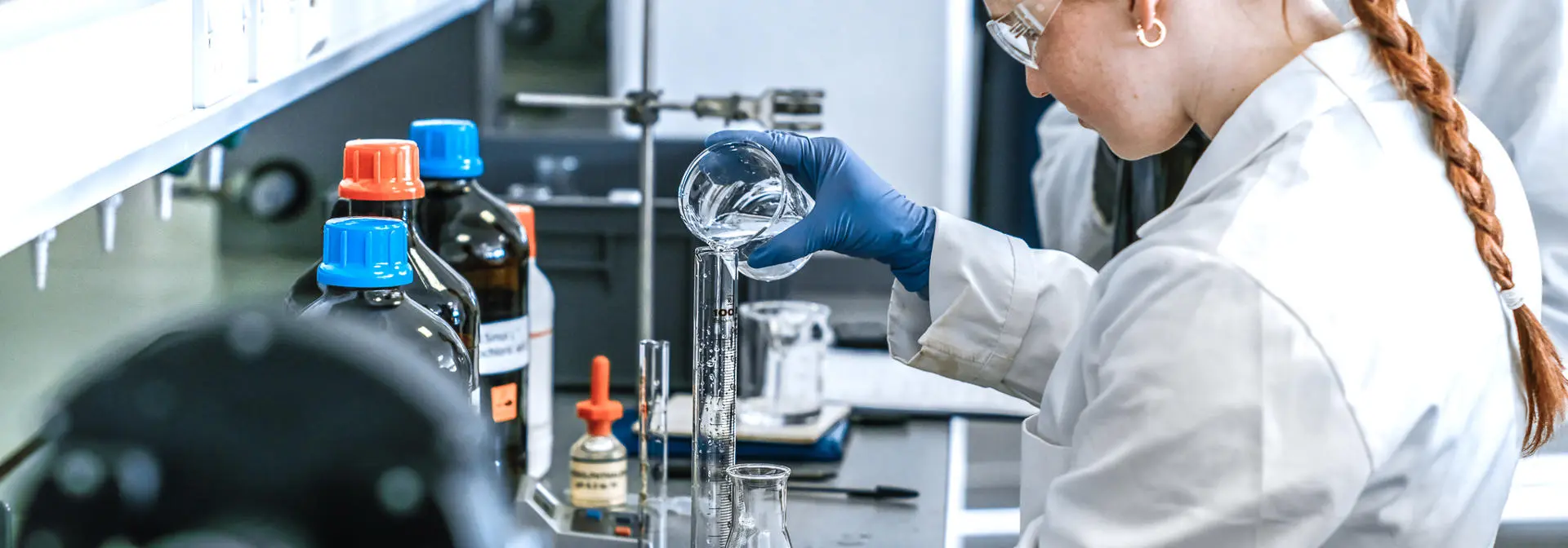 Chemistry student pouring liquid into a measuring flask