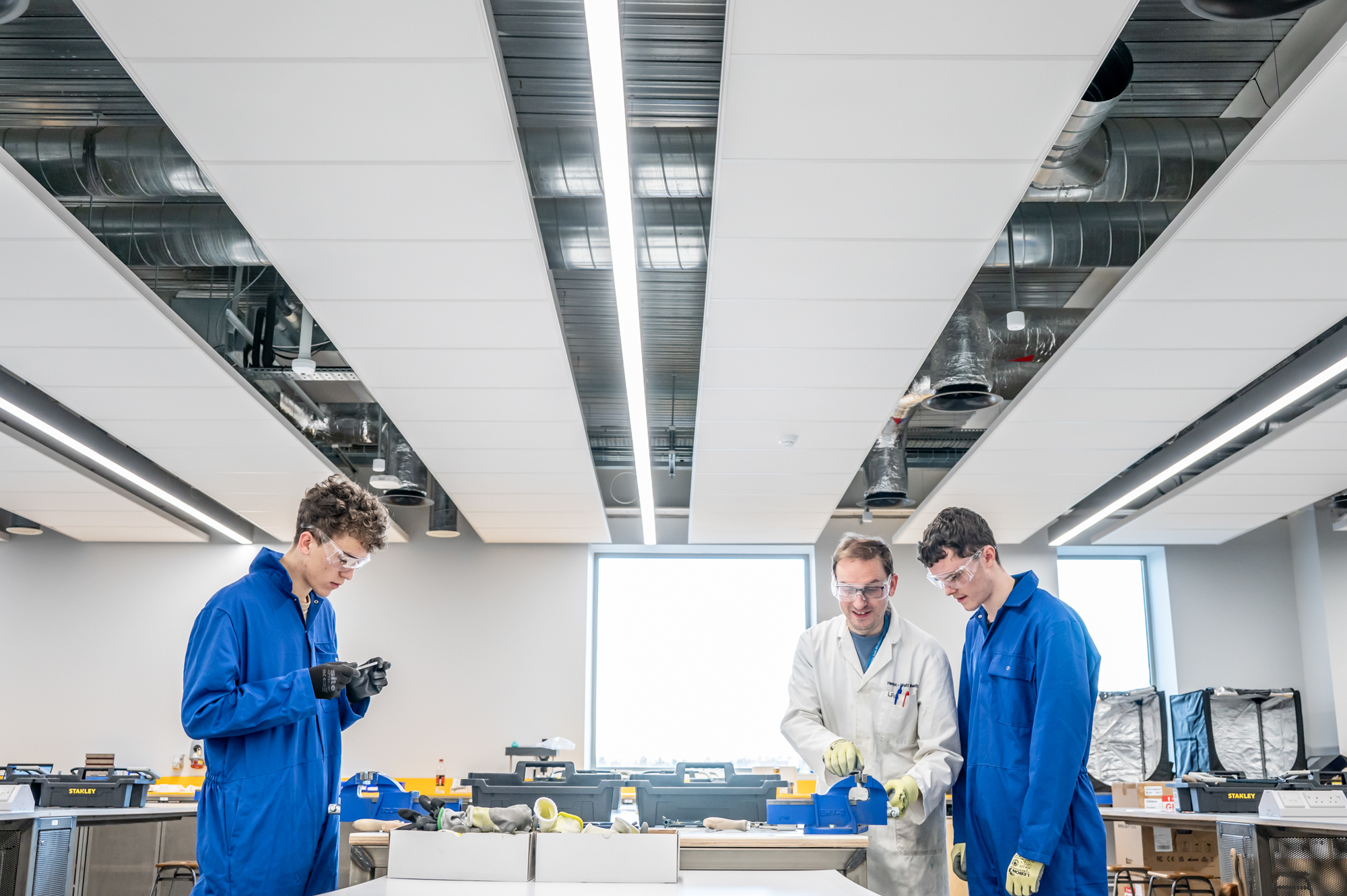 A professor guiding students on equipment use in maker lab