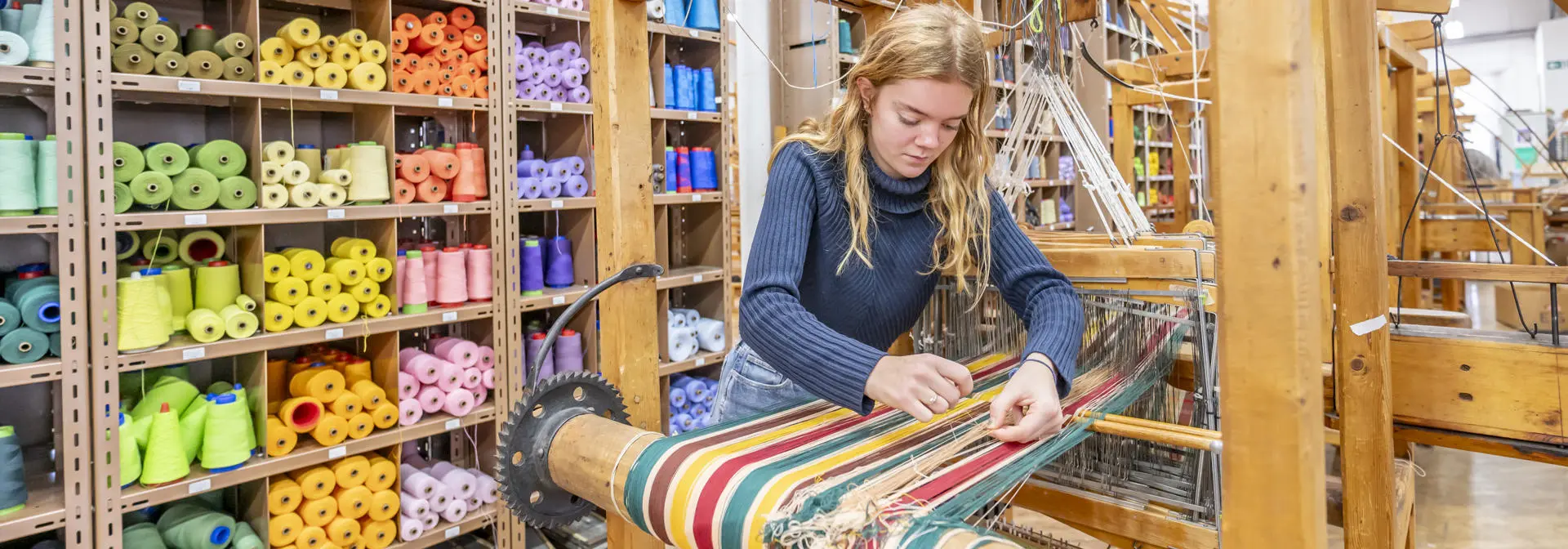Textiles student working with a loom in the Weave Shed