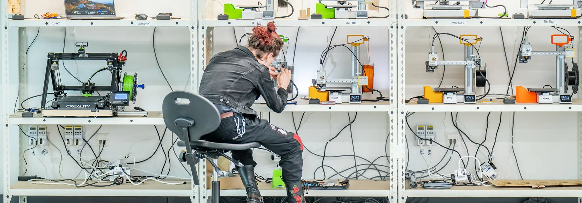 A wall of 3d printers, a person working on one of them