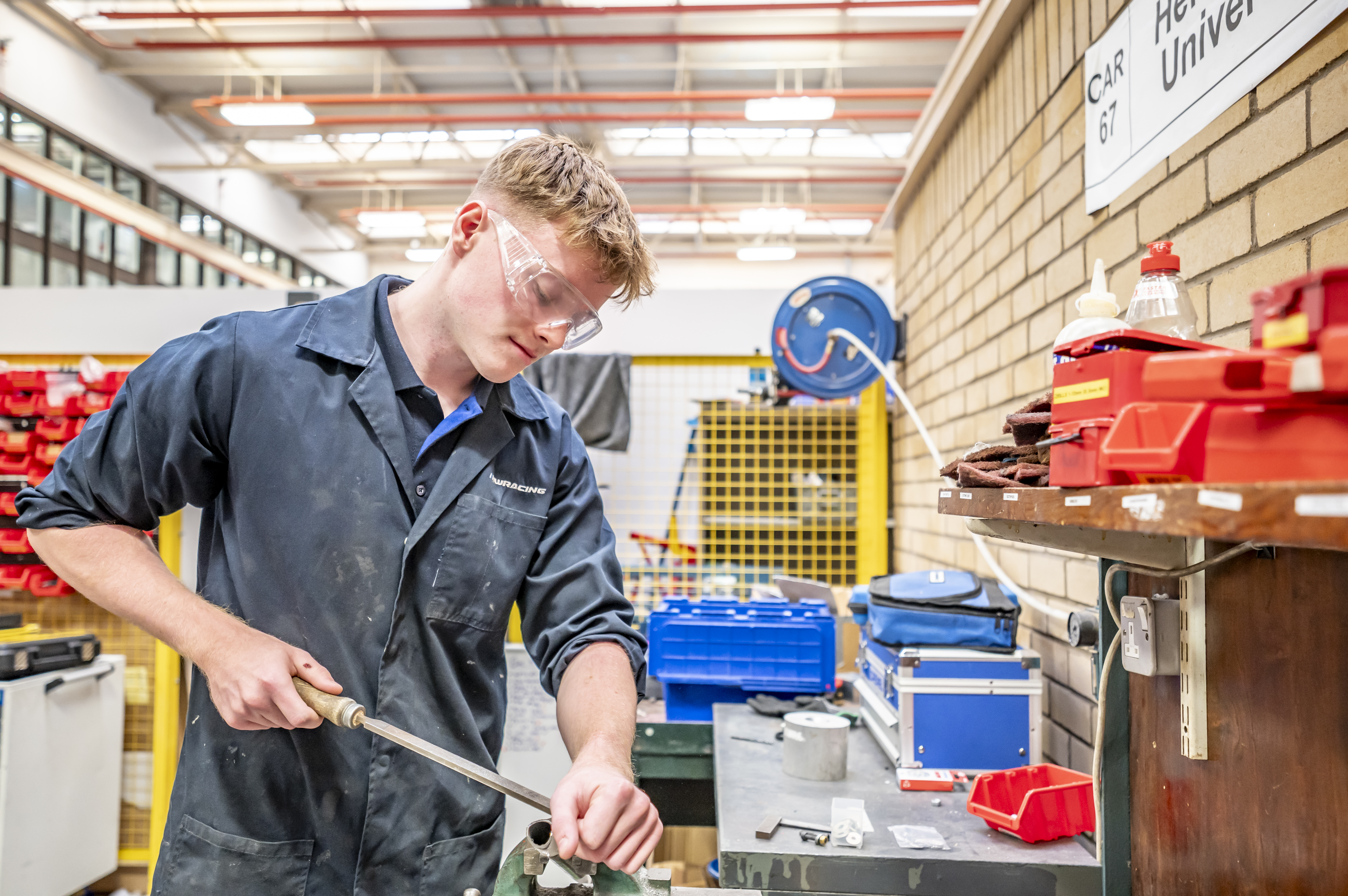 Student with goggles and a coat on working in a lab