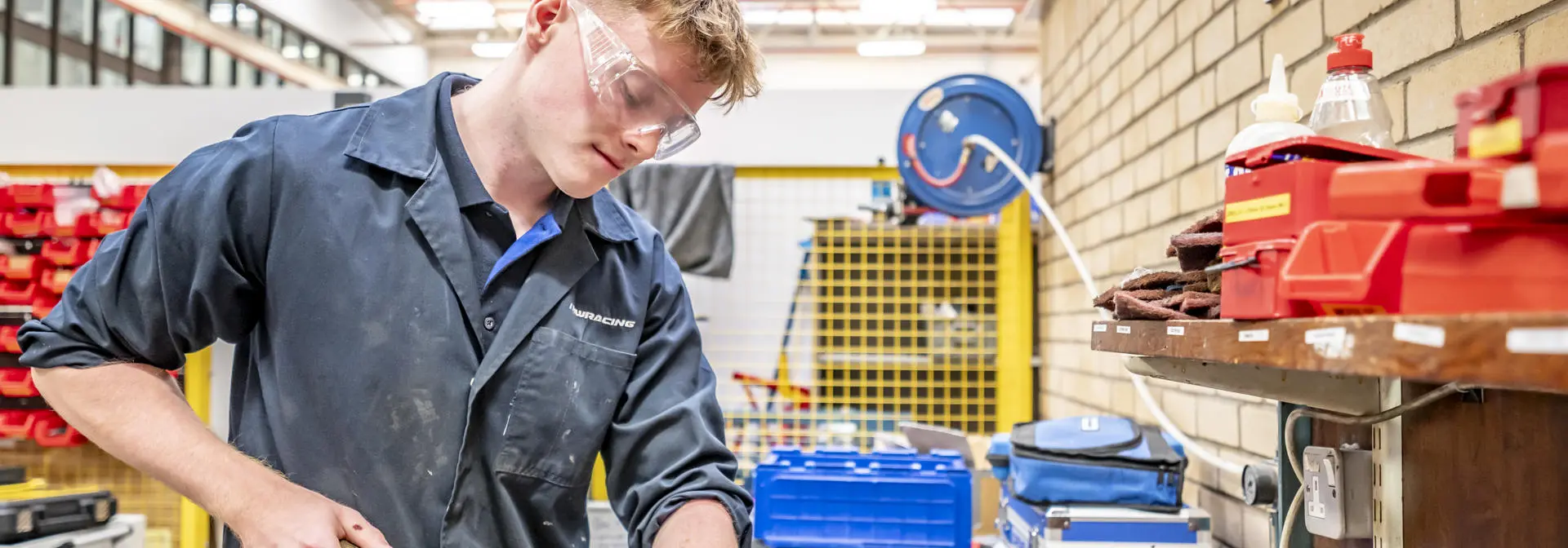 Student with goggles and a coat on working in a lab