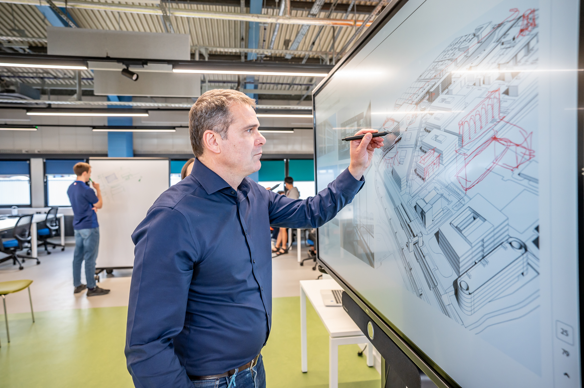 Person writing over a 3d model of buildings in a monitor