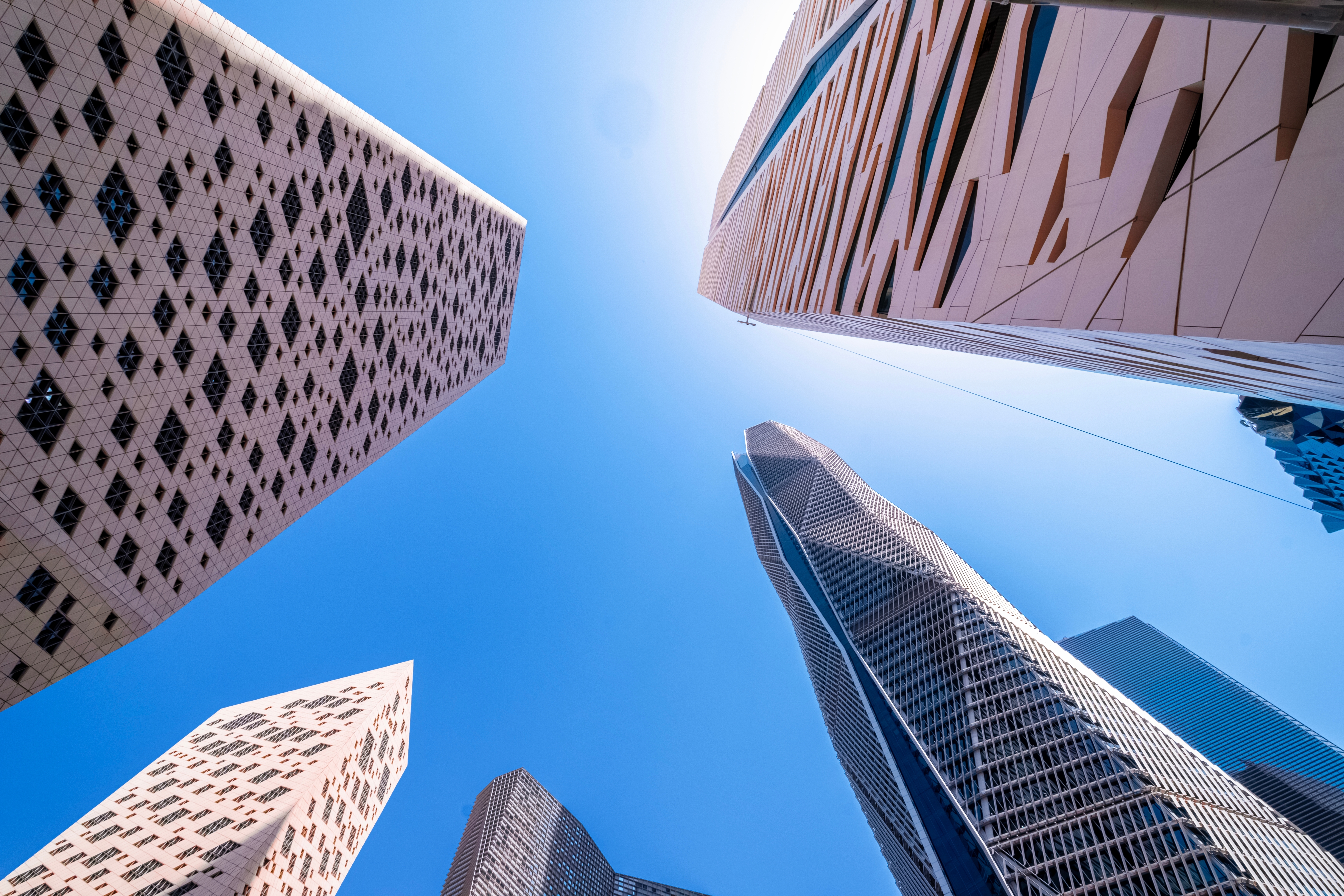Upward view of several modern skyscrapers converging toward the sky