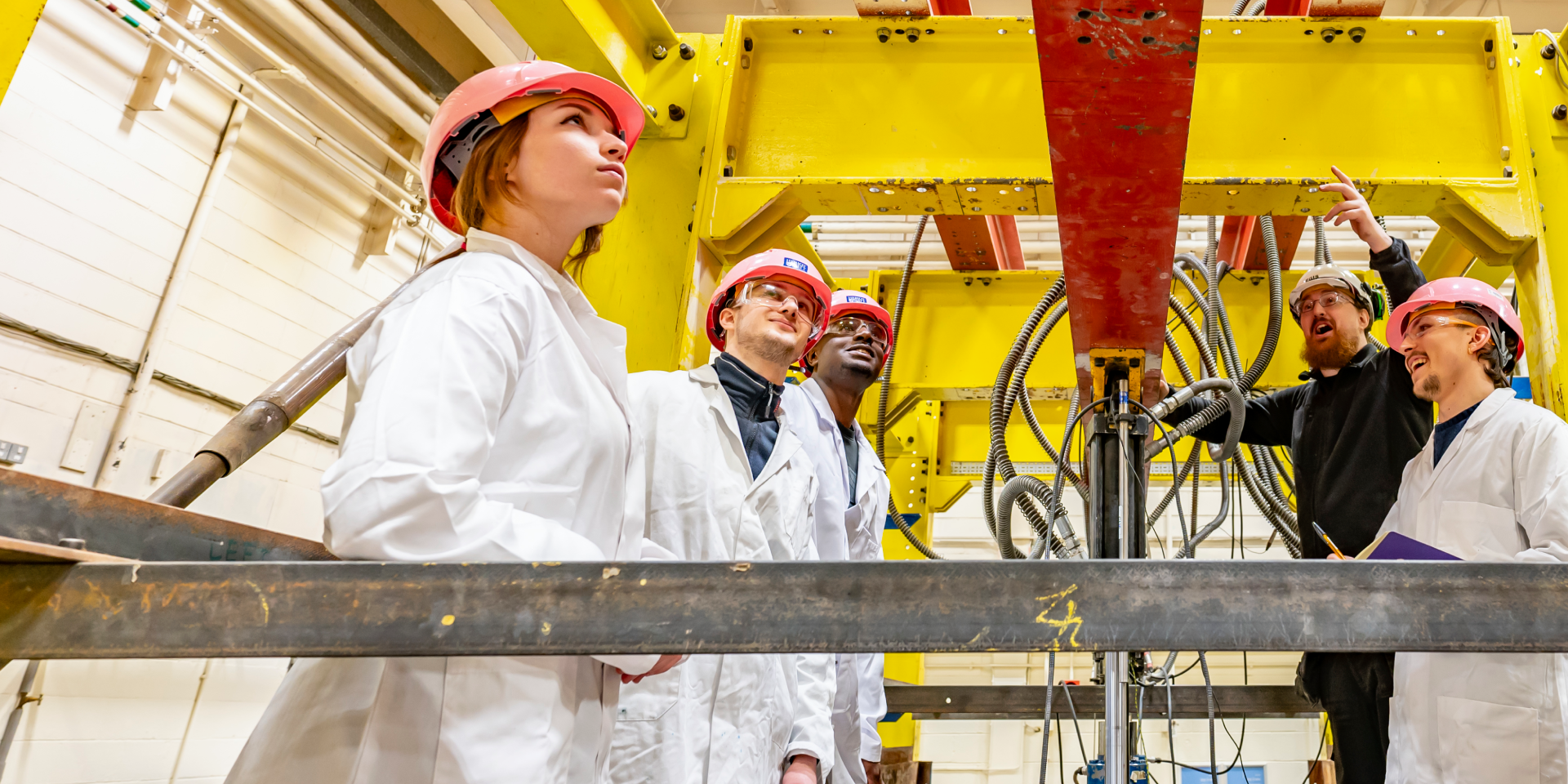 A group of students and a technician in the building workshop