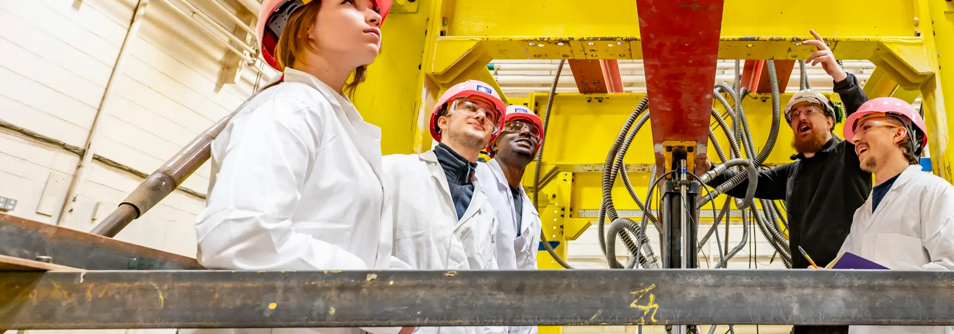 A group of students and a technician in the building workshop