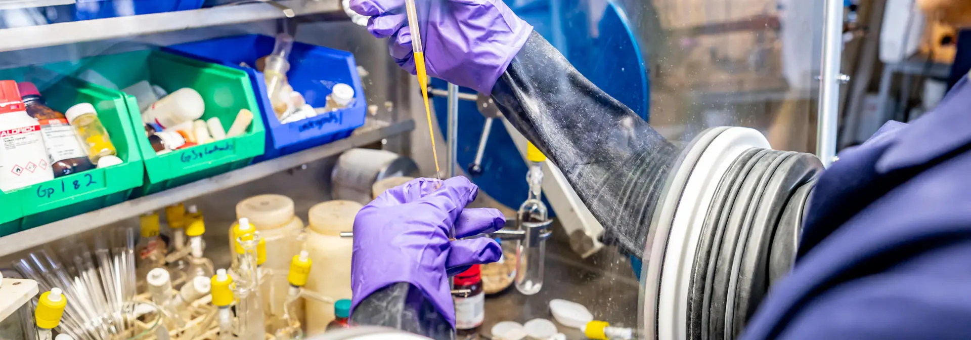 A student in a chemistry lab using an isolation glove box