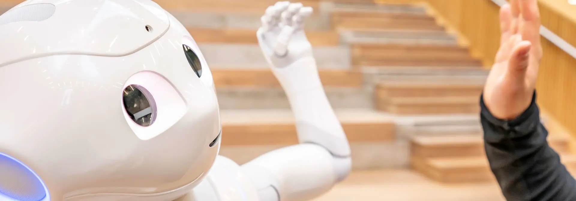 student giving a humanoid robot a high five
