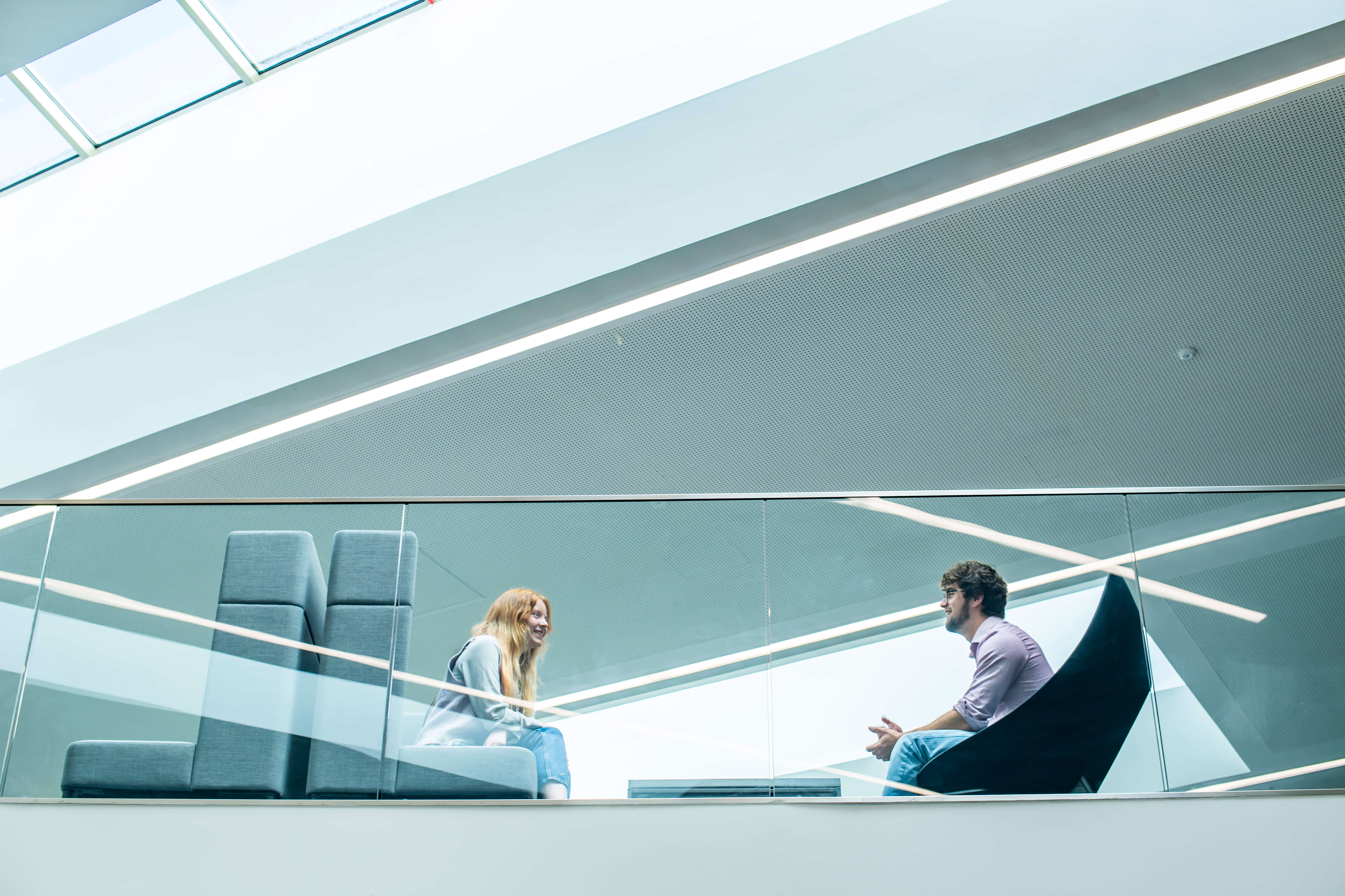 Two students seated in conversation on a mezzanine floor