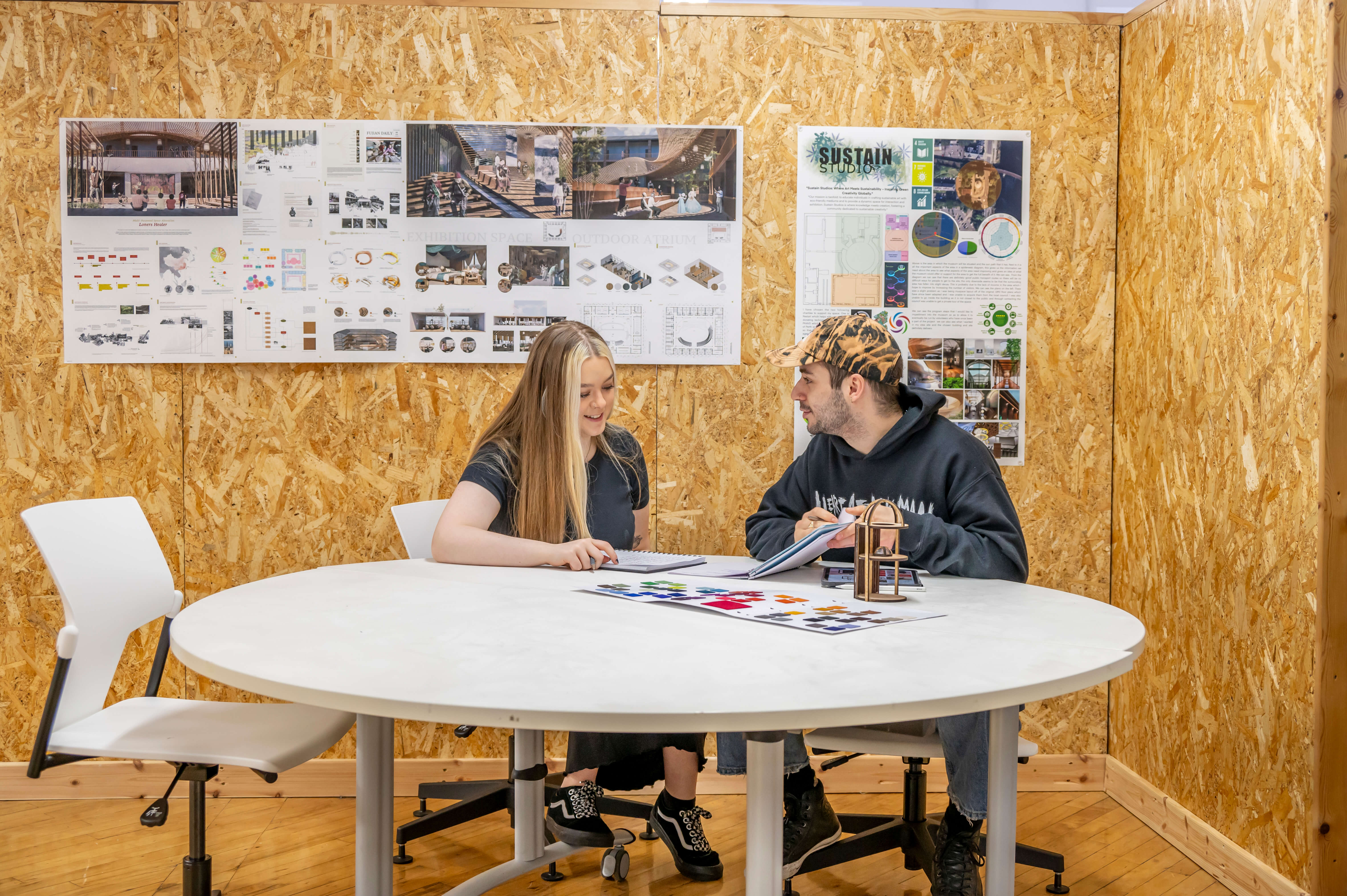 two students discussing on a roundtable with architecture models
