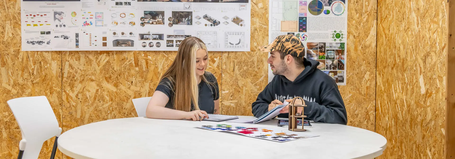 two students discussing on a roundtable with architecture models