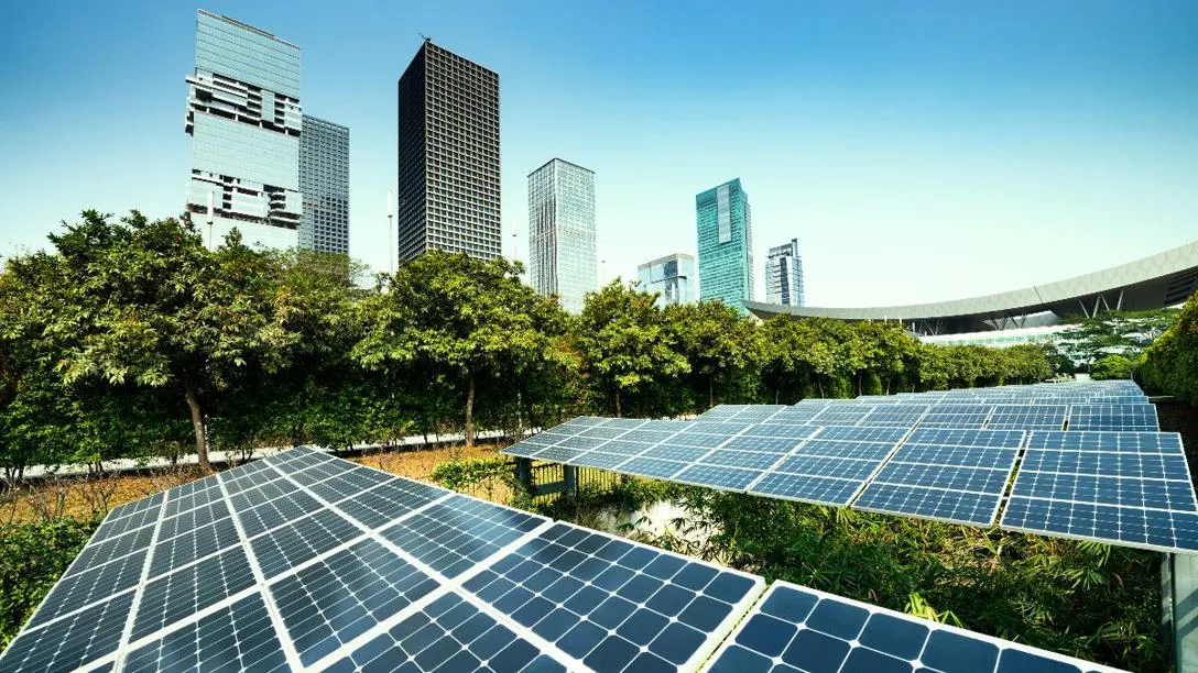 Solar panels on ground with tall buildings in distance