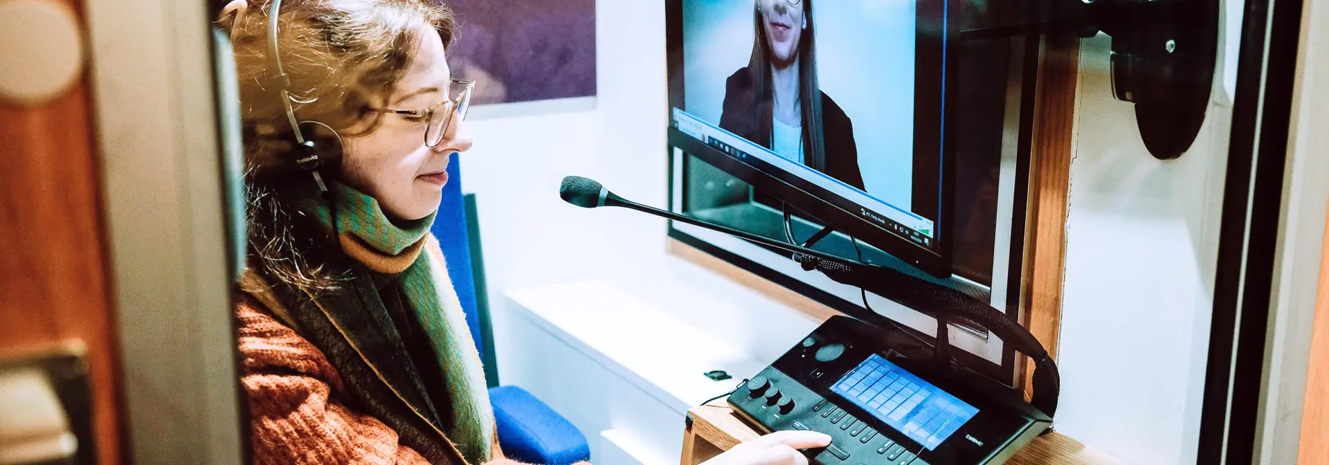 An individual in a booth listening and interpreting with sound equipment.