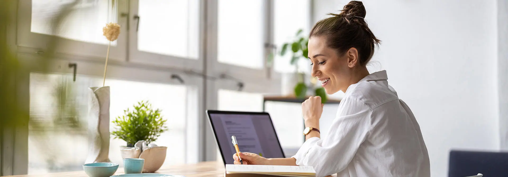 An individual works in a bright room on a laptop