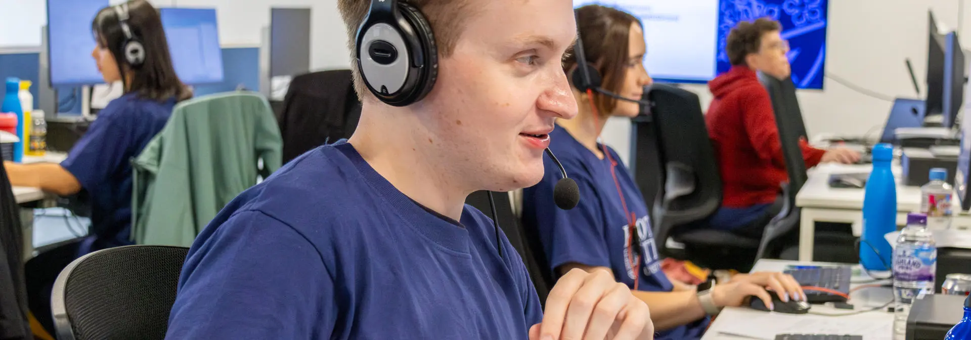 Staff working at a computer in an office with a headset.