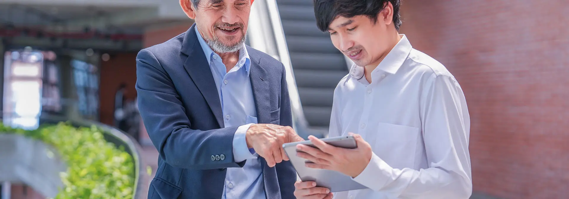 Two individuals in conversation over an ipad.