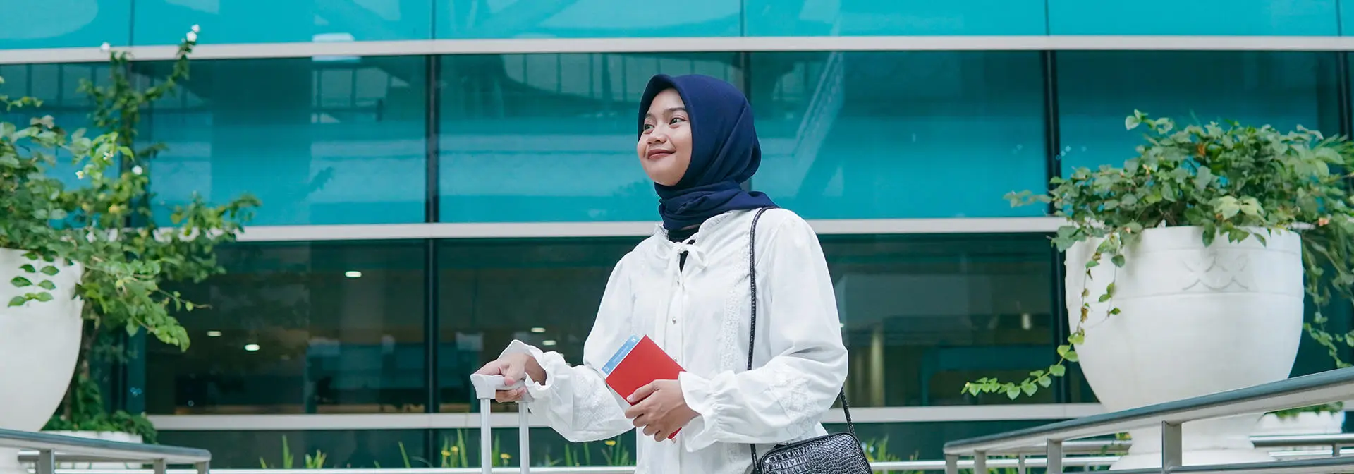 A woman wearing a headscarf carrying luggage.