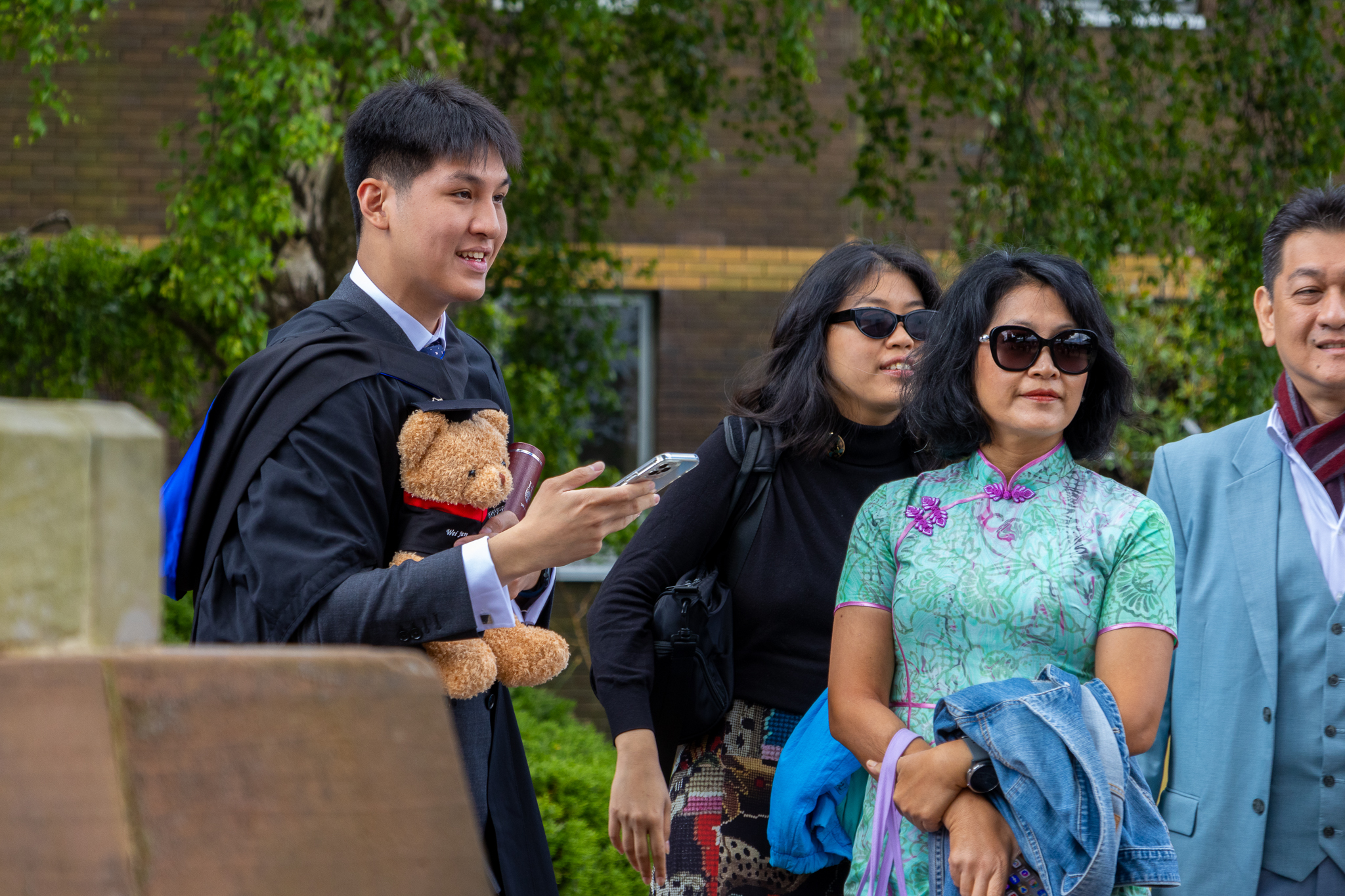 A student holding Heriot-Watt bear with family on graduation day.