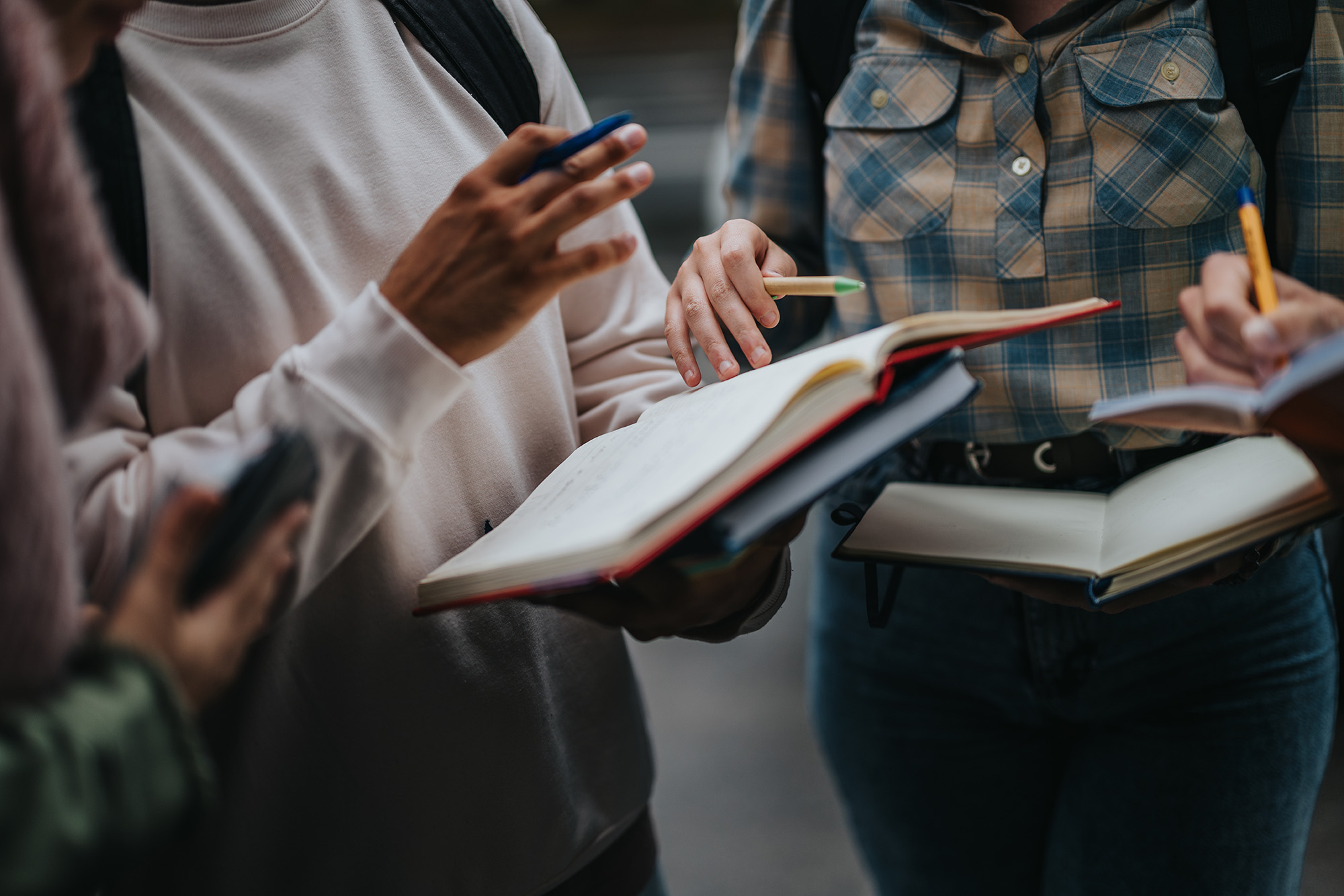 Three students in a group discussion holding books.