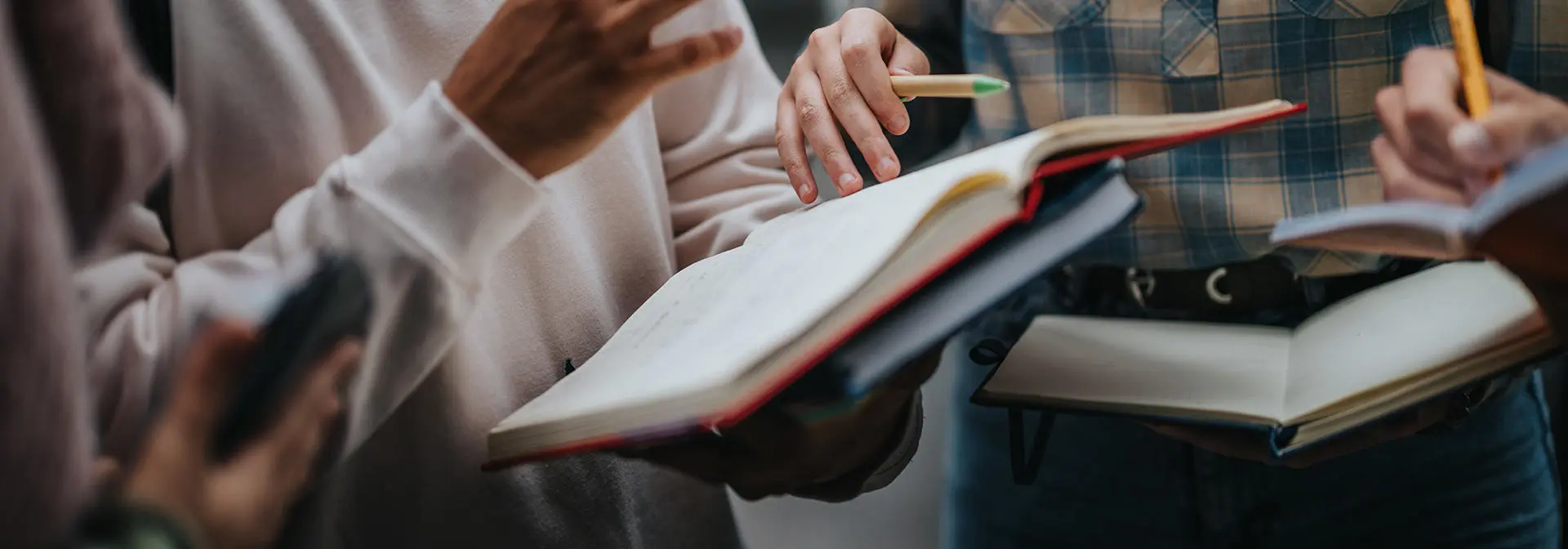 Three students in a group discussion holding books.