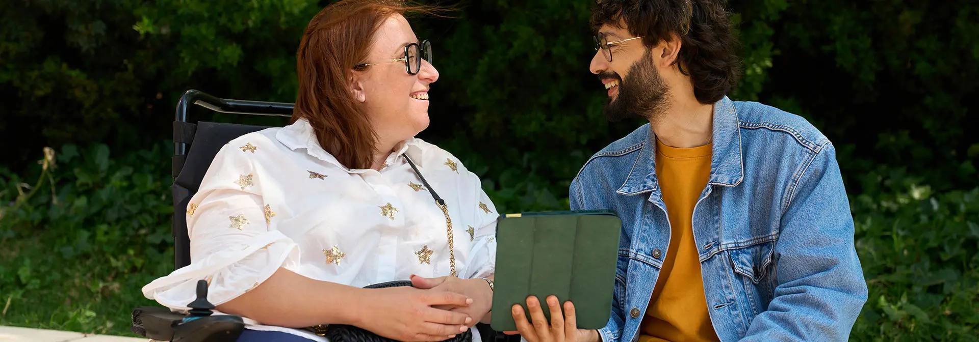 Two people smiling as they discuss over an ipad.
