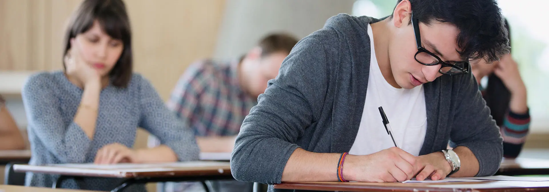 Students in an exam hall writing answers.