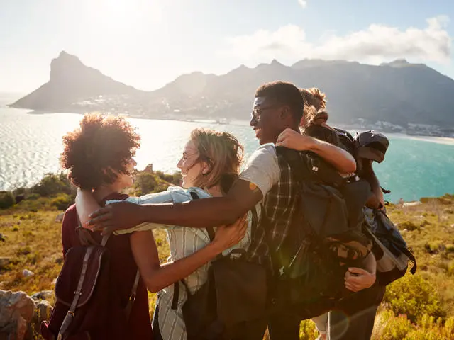 Five students in a huddle at the top of a cliff outlooking onto the sea.