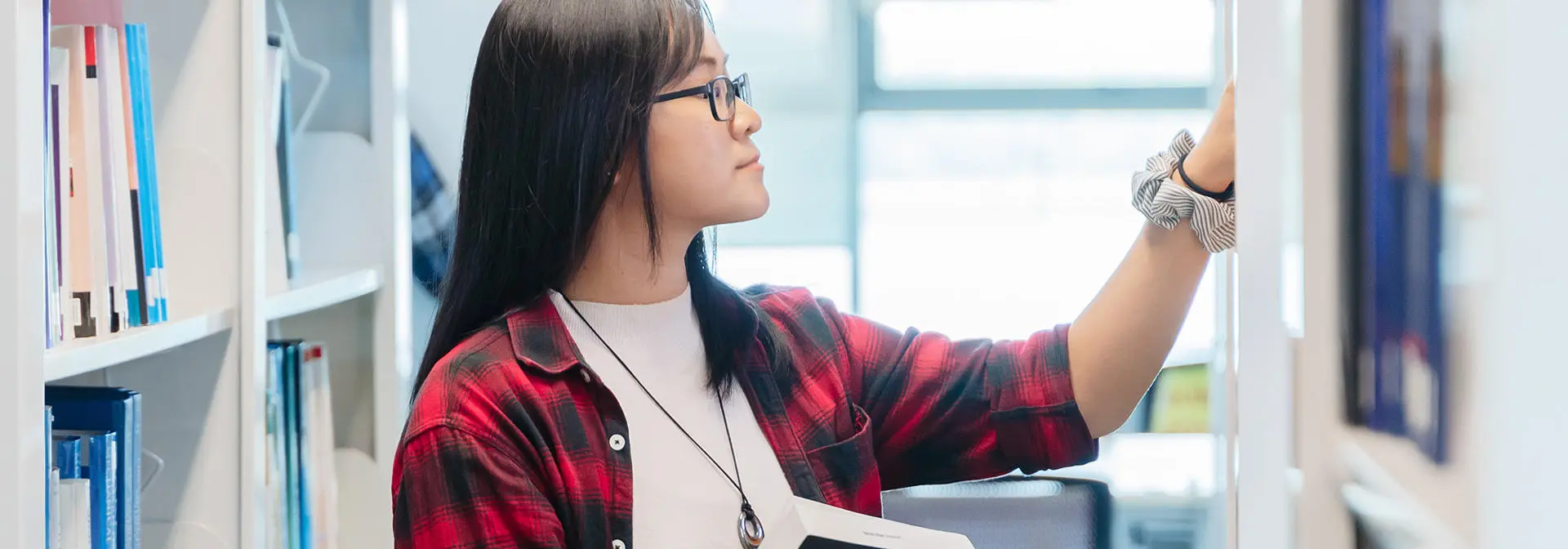 A student looking through books in Malaysia campus library.