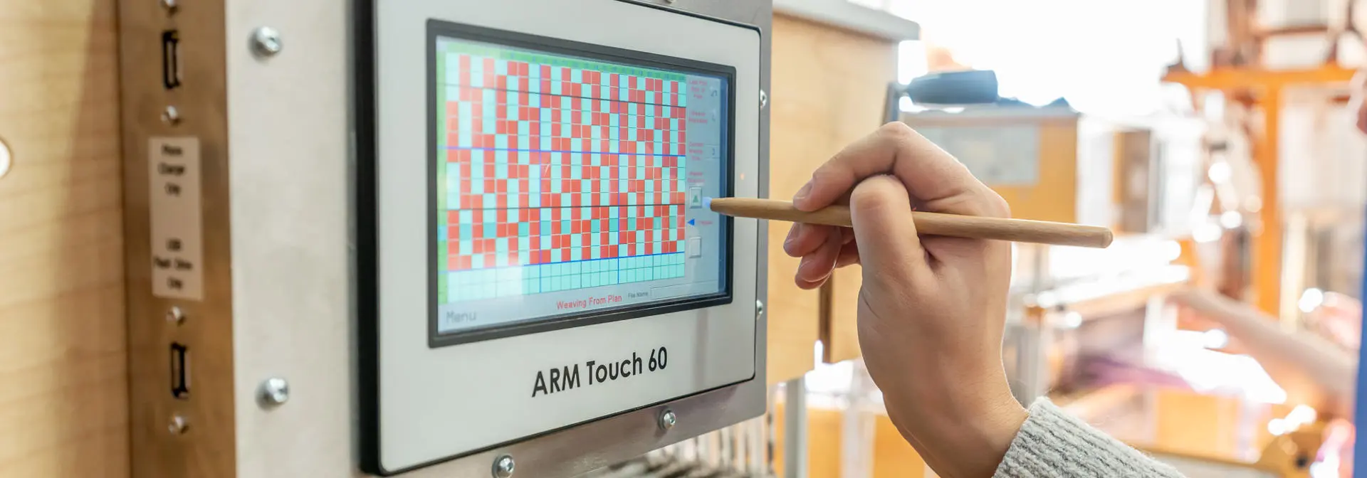 A computer screen on a weaving machine being used with a stylus.