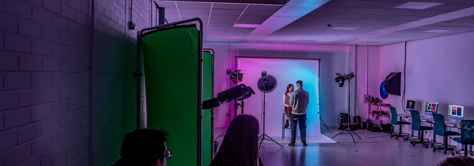 Students working with a green screen and camera as part of a photography shoot.