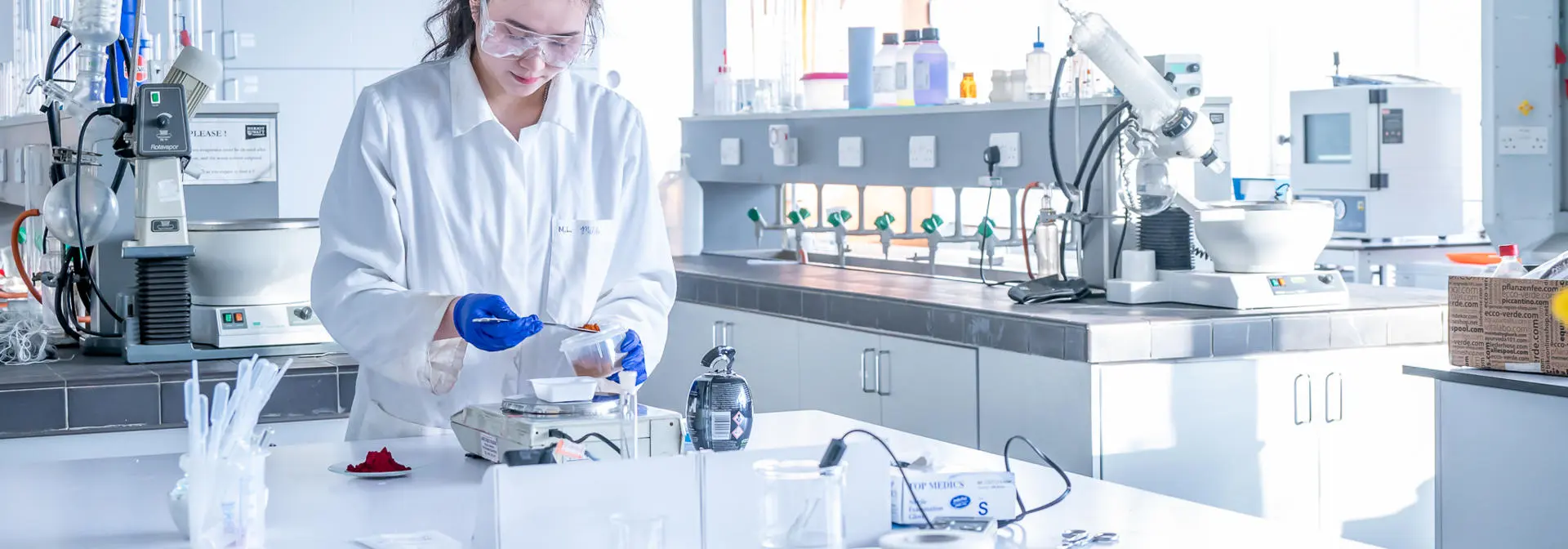 An individual measures coloured dye into a beaker in a chemistry laboratory.