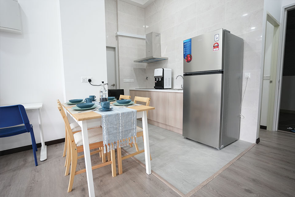 A compact kitchen featuring a refrigerator, a dining table, and chairs, designed for efficient use of space.