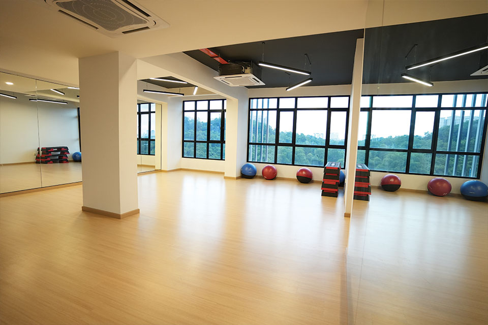 A well lit studio with a large window, highlighting the warm tones of the wooden floor beneath.