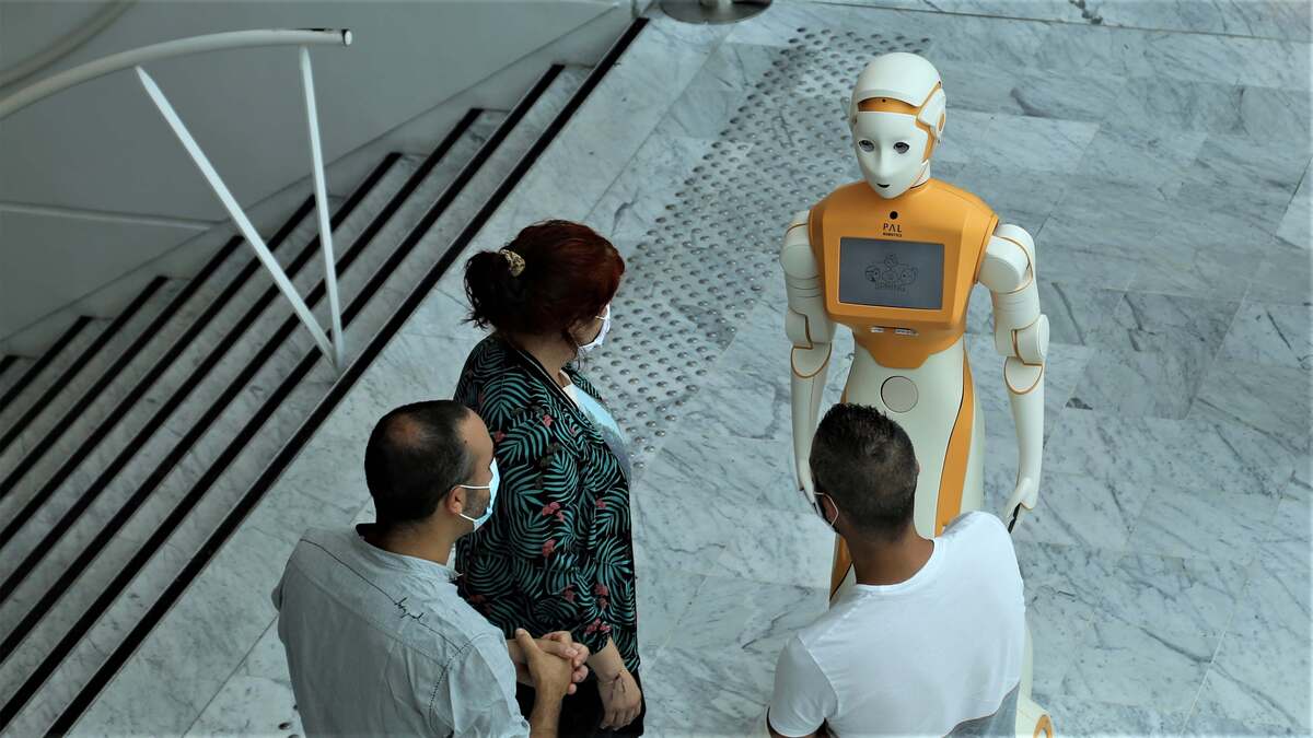 Three adults stand around an ARI humanoid robot
