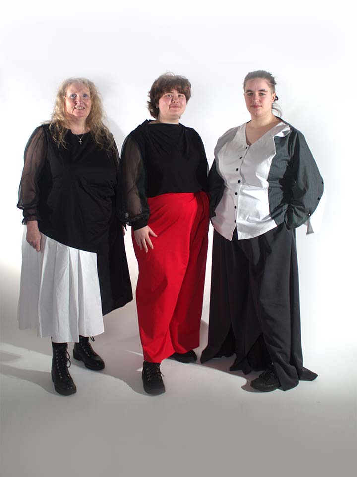 Three women in black, white, and red clothing standing together.