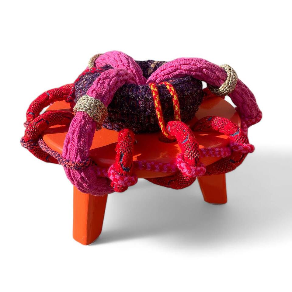 A vibrant stool with a woolen rope design, featuring a captivating pink and red and purple colour scheme.
