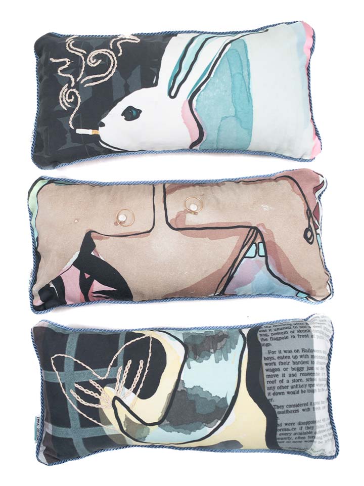 Three fabric pillows, each with a unique design.