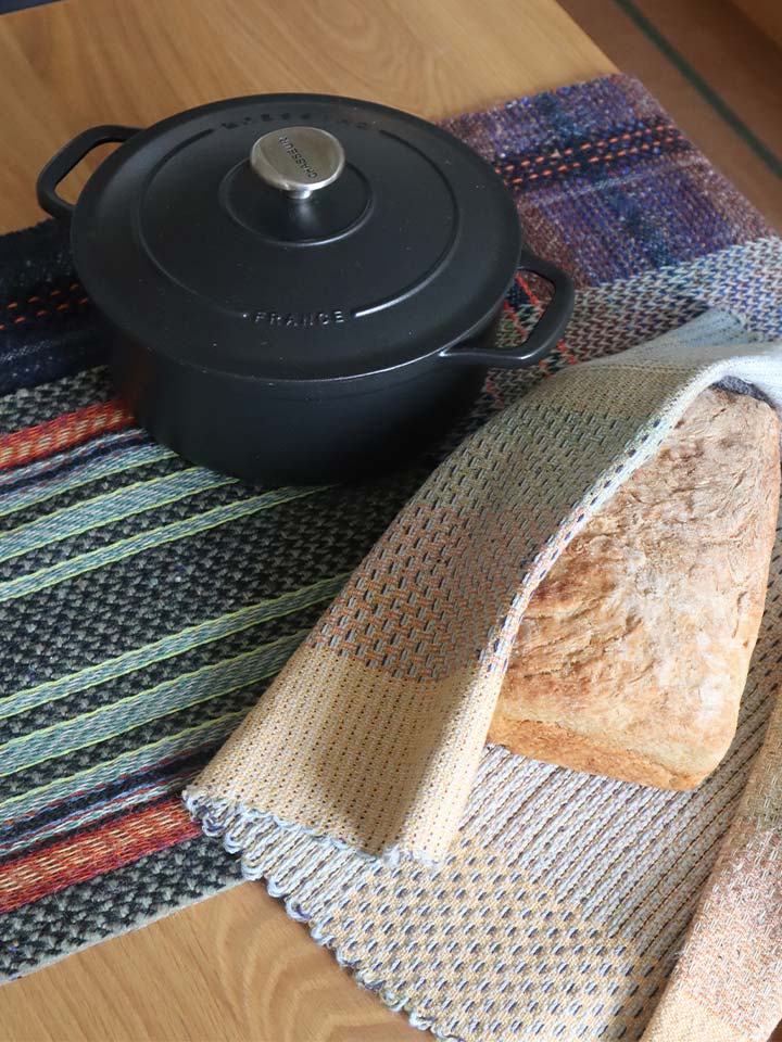 A loaf of bread and a pot displayed on an attractive textile .