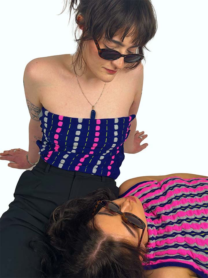 Two women lying down on the ground, one with sunglasses and the other with a hat.