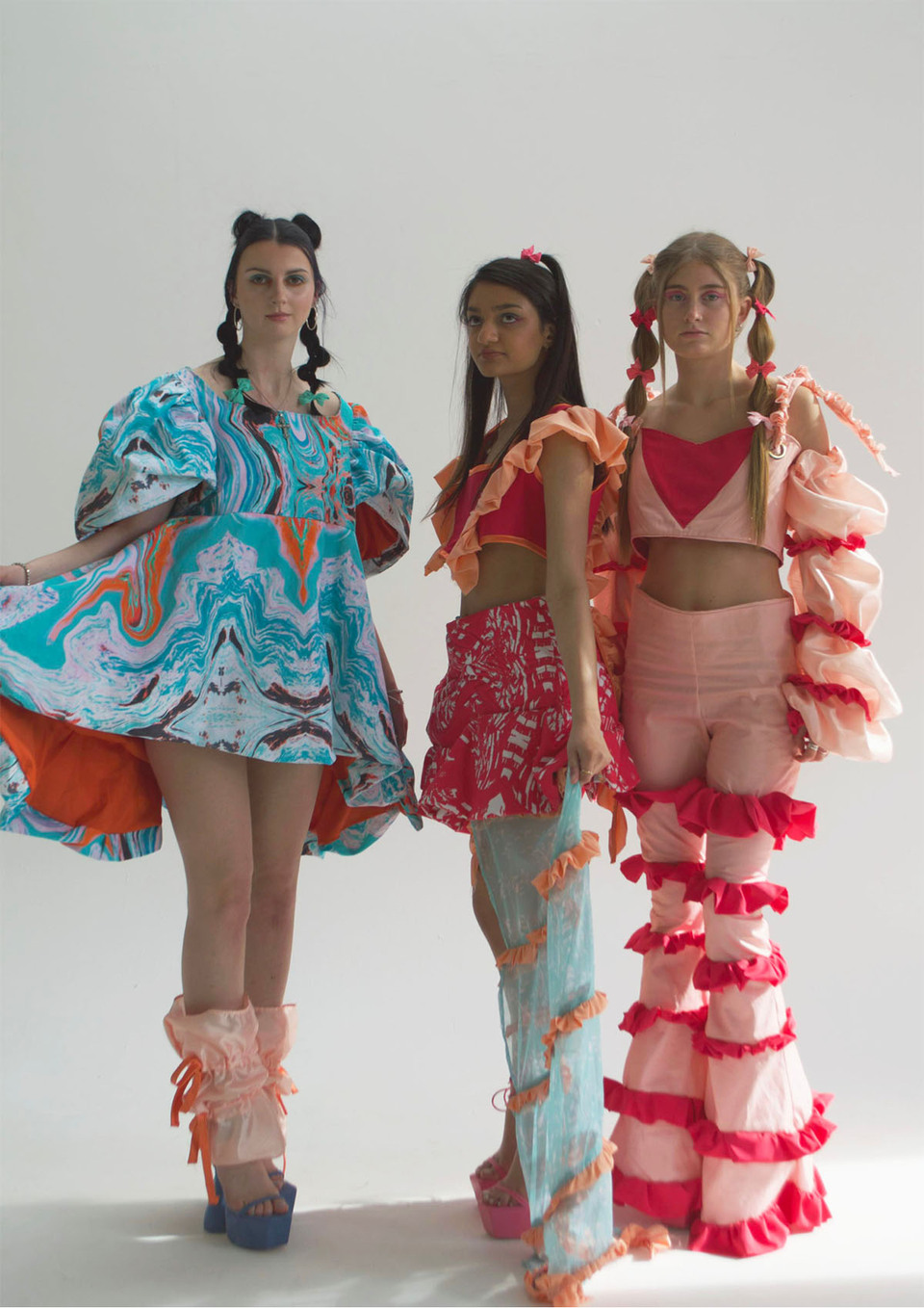 Three women model tops, trousers, skirt and dress in blue, pink and peach design from 'Forget Me Not' a collection by Jessica Neilson 