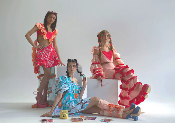 Three women model tops, trousers, skirt and dress in blue, pink and peach design from 'Forget Me Not' a collection by Jessica Neilson 