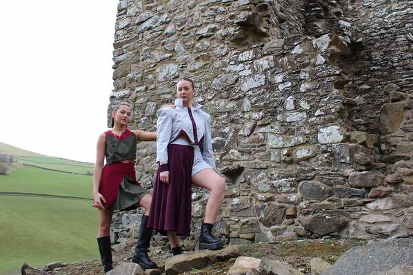 Two women model Karen Heath designs - dress, skirt, top and jacket standing on the ruins of a castle
