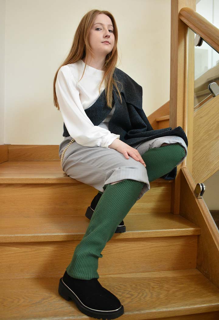 A woman sitting on stairs, wearing green socks.