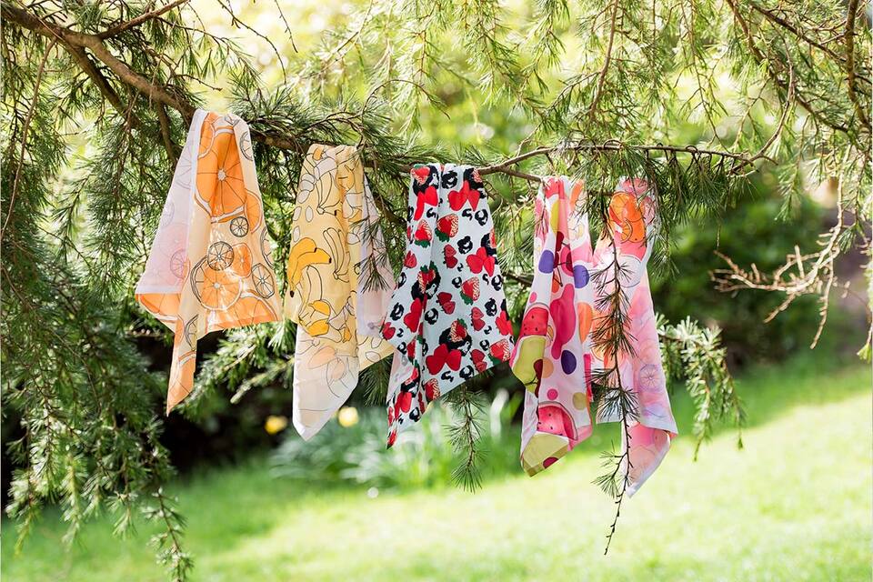A vibrant collection of scarves adorns a tree, creating a colorful and eye-catching display.